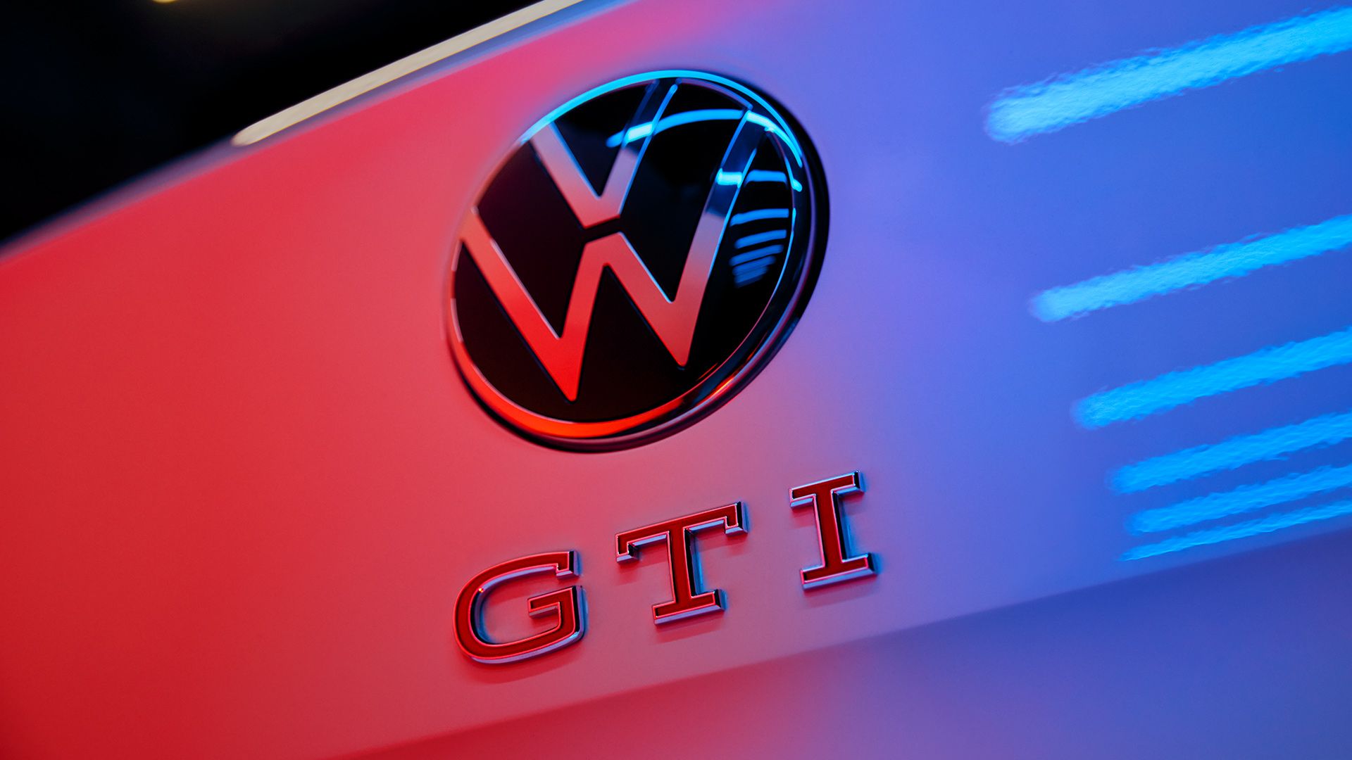 Detajlni posnetek logotipa VW in napisa GTI z rdečimi črkami na zadku Pola GTI.