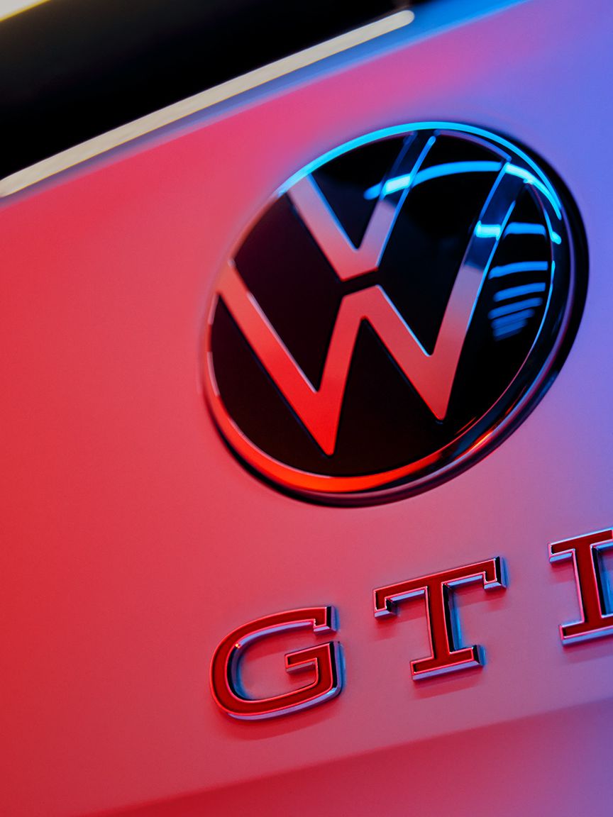 Detajlni posnetek logotipa VW in napisa GTI z rdečimi črkami na zadku Pola GTI.